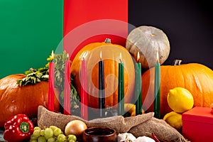 Composition of halloween decoration with candles and pumpkins on tricoloured background