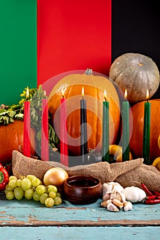 Composition of halloween decoration with candles and pumpkins on tricoloured background