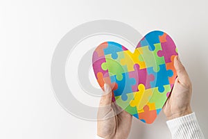 Composition of hands holding jigsaw puzzle heart on white background with copy space