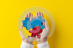 Composition of hands holding jigsaw puzzle pieces on yellow background with copy space