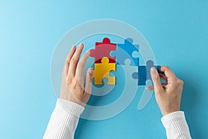 Composition of hands putting jigsaw puzzle pieces together on blue background with copy space