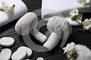 Composition with herbal massage bags and other spa products on black wooden table