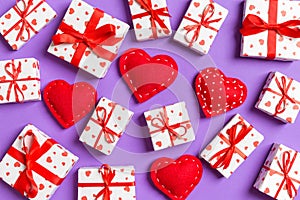 Composition of holiday white gift boxes and red textile hearts on colorful background. Valentine\'s day concept