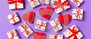 Composition of holiday white gift boxes and red textile hearts on colorful background. Valentine\'s day concept