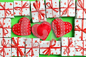 Composition of holiday white gift boxes and red textile hearts on colorful background. Valentine\'s day concept