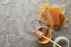 Composition honeycombs, honey and dipper on gray background