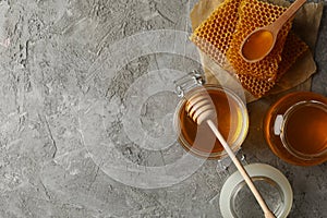 Composition with honeycombs honey and jars on gray background