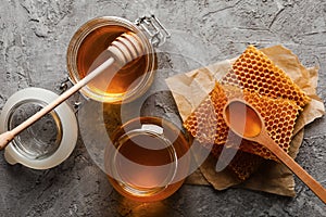 Composition honeycombs, honey and jars on gray background