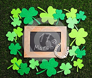 Composition with horseshoe and chalkboard on grass. St. Patrick`s Day celebration