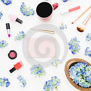 Composition of hydrangea flowers with feminine cosmetics, notebook and mug of coffee on white background. Flat lay, top view.