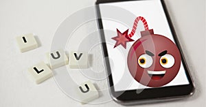 Composition of i luv you text on squares with bomb emoji over smartphone