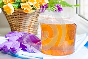 composition of jar sugar paste or wax honey for hair removing with purple gloves and flowers - depilation and beauty concept