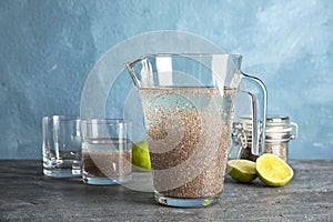 Composition with jug of water and chia seeds on table against color