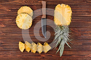 Composition with knife and sliced pineapple on wooden background, flat lay