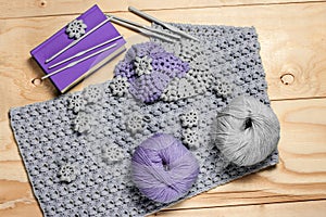 Composition of knitting accessories and needlework elements. Grey and purple napkins, balls of wool yarn, book, hooks on light