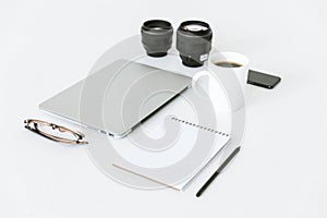 composition with laptop, notepad, camera lenses and cup of coffee