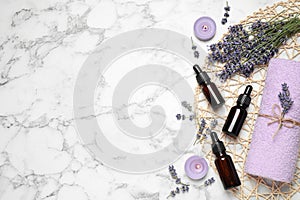 Composition with lavender flowers and natural essential oil on white marble table. Space for text