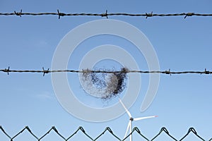 Composition of litter, barbwire, metal fence and a wind turbine