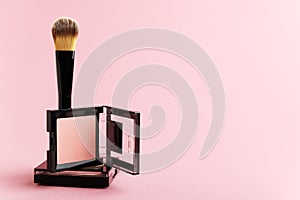 Composition with makeup items on a white background. Black brush, makeup tool, packing of blush and powder on a pastel backdrop.