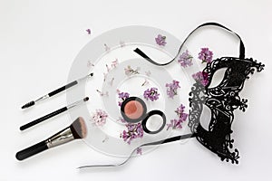 A composition of a masquerade black mask, spring flowers on a white background.