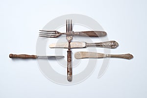 Composition of metal vintage knives with an ornament and old forks with wooden handles on a gray background with space