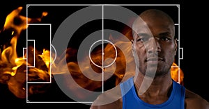 Composition of mixed race basketball player over basketball court with flames on black background