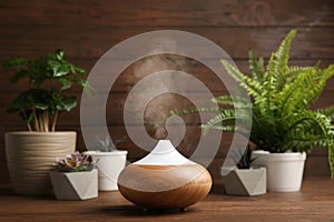 Composition with modern essential oil diffuser on wooden table against brown background, space for photo