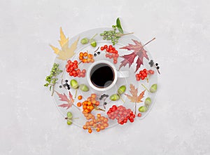 Composition of morning coffee mug, autumn leaves and berry on light background overhead view. Cozy breakfast. Flat lay style.