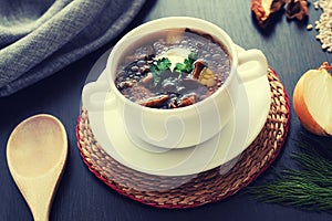 Composition with mushroom soup in a Cup with handles, fresh and dried mushrooms, on a wooden table, on a background of