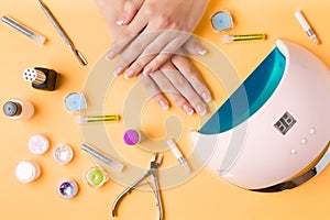 Composition for nail care, female young hands, French manicure, gel polish, lamp for nails and equipment for nail care. Flat lay