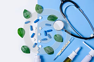 Composition nasal spray, throat spray, stethoscope, white jar with pills, thermometer nature green leaf