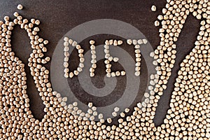 Composition of natural chickpeas with kitchen utensils, spoon and wooden fork on rustic textured bottom. View from above with