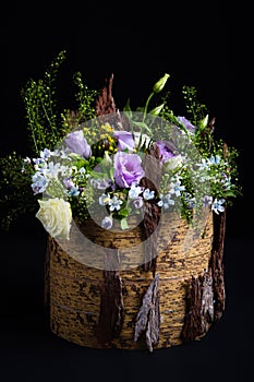 Composition of natural flowers in a decorative vase made of tree bark