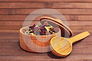 Composition of natural tea with a leaves of rose. Macro photo of tea petals in a wooden board. Tea with petals of Sudanese rose, b
