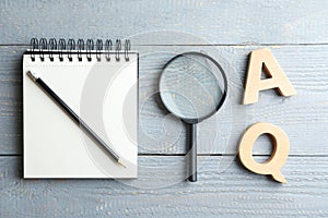 Composition with notebook, magnifier glass and letters on light grey wooden table. Find keywords concept