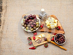 Composition with olive wood, olives, cheese pieces in olive oil, bread and spices