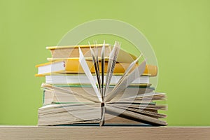 Composition with open book, hardback books on wooden table and green background. Back to school..Education background.