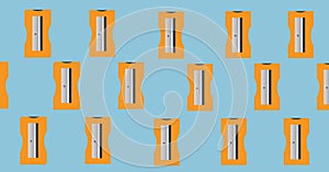 Composition of orange pencil sharpeners repeated in rows on blue background