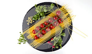 Composition of pasta fresh tomato, pepper, radish on black stone board, white background.