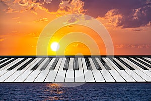 Composition of piano keyboard on marine background with a setting sun.
