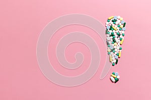 Composition of pills and capsules on a pink background in the form of an exclamation mark. Psychological help. Copy