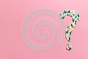 Composition of pills and capsules on a pink background in the form of a question mark. Psychological help. Copy space