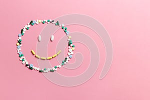 Composition of pills and capsules on a pink background in the form of a smile. Happy emotions. Psychological help. Copy