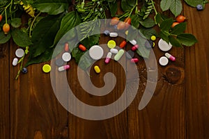 Composition with pills and herbs on wooden background