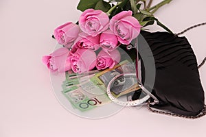 Composition with a pink roses bouquet, clutch, and cash