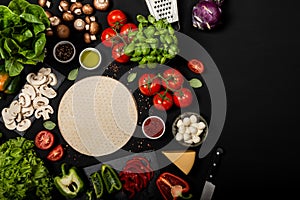 Composition with pizza dough and raw ingredients for cooking italian pizza. Top view on a black background.