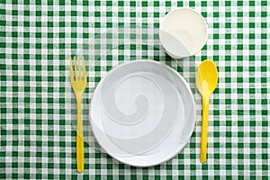 Composition with plastic dishware on checkered tablecloth