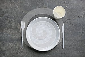 Composition with plastic dishware on grey background, flat lay.