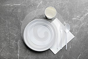 Composition with plastic dishware on grey background, flat lay.