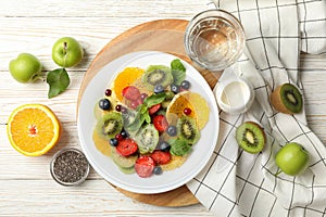 Composition plate of fresh fruit salad on white wooden table, top view